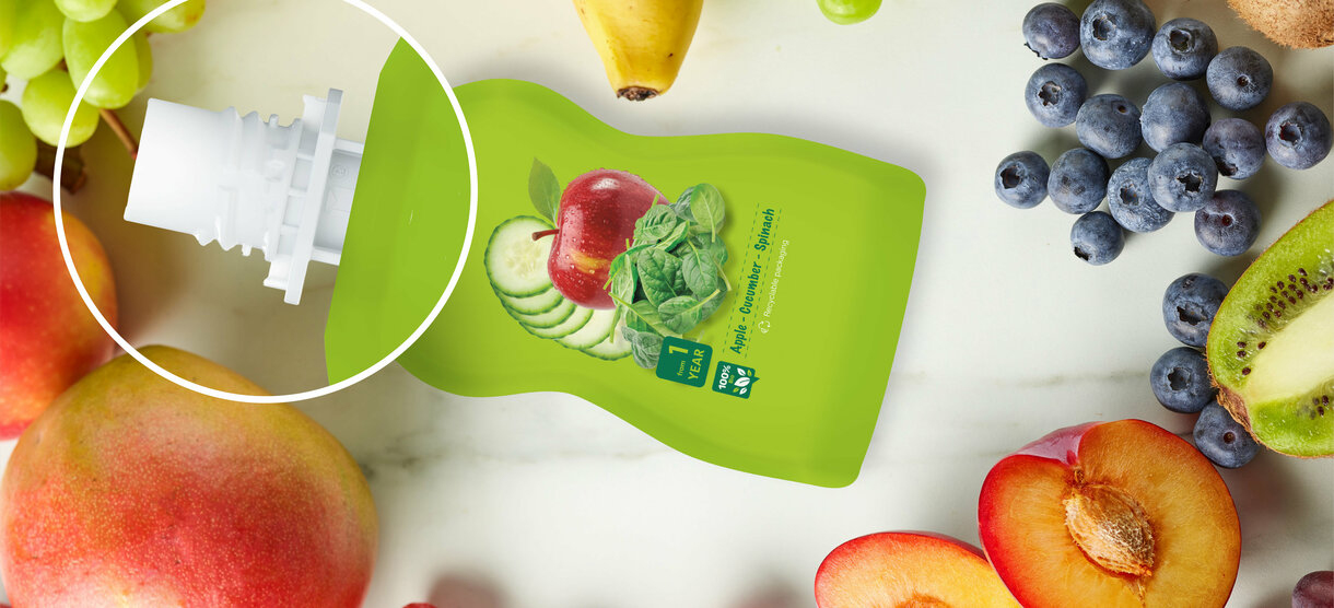 Spoutbeutel Grafik mit Spout in der Vergrößerung und Obst im Hintergrund